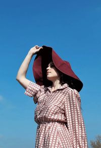 Low angle view of woman standing against blue sky