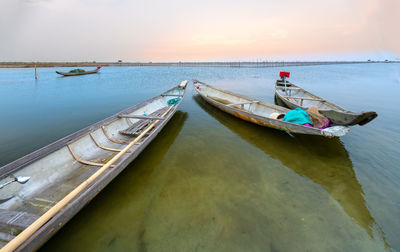 Boat moored in sea against sky during sunset