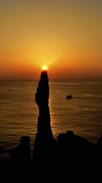 Silhouette of rocks on beach during sunset