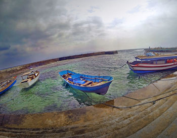 Boats in sea against cloudy sky