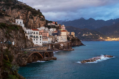 View of buildings by sea against cloudy sky