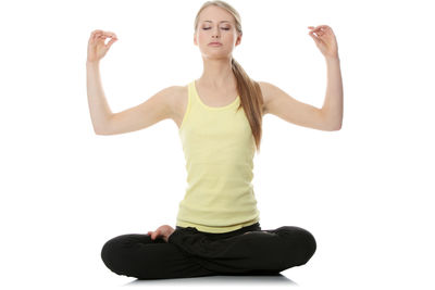 Young woman with arms raised against white background