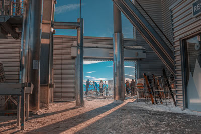 People standing by building in city against sky