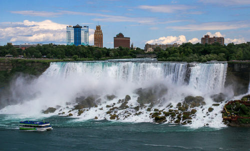 Maid of the mist cruise  passing american falls of niagara falls with new york in the background.