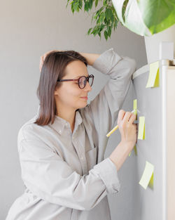 Smiling woman writing on adhesive note