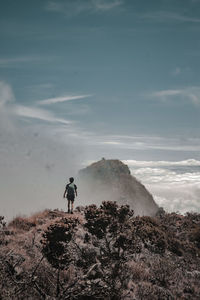 Man standing on rock on land against sky