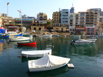 Boats moored in canal by buildings in city