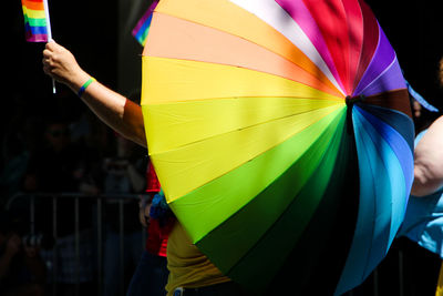 Cropped image of people holding multi colored umbrella