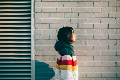 Rear view of woman standing against brick wall