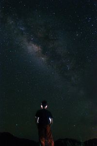 Rear view of man standing against star field at night