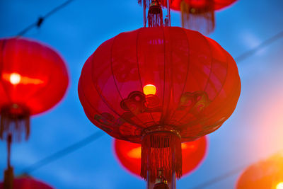 Low angle view of illuminated lanterns hanging against blue sky