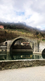 Arch bridge over river against sky