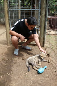 Full length of boy playing in fence with a puppy leopard