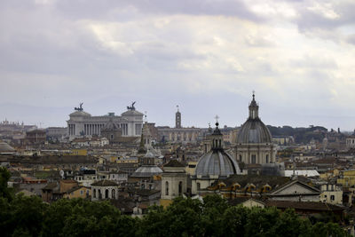 View of buildings in city against cloudy sky