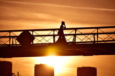 Silhouette people standing on bridge against sky during sunset