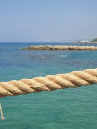 Close-up of rope on shore against sea