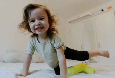 Happy girl with a cast on her leg on the bed.