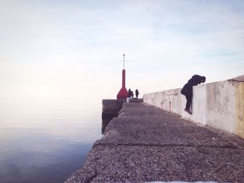 Person climbing on retaining wall against sea at gabicce mare