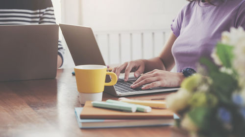 Midsection of woman using laptop on table