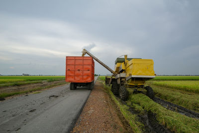 Road amidst field against sky