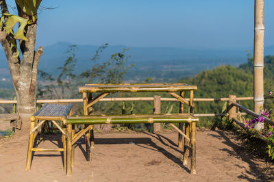 Empty chairs and table by sea against blue sky