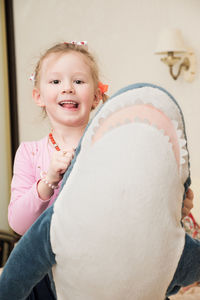 Portrait of smiling girl holding stuffed toy at home