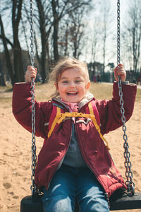 Portrait of smiling girl playing on swing at playground