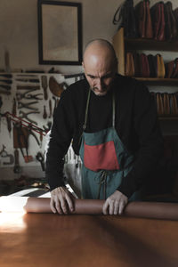 Man wrapping leather fabric in atelier