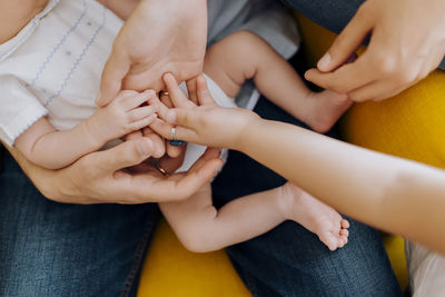 Close up newborn baby hand and his parents and older sister hands