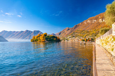 Comacina island, photographed in autumn, with trees, boats and piers around.