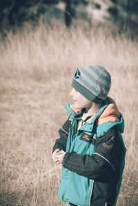 Side view of smiling boy standing on grassy field