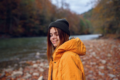 Young woman standing by tree during autumn