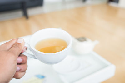 Midsection of person holding tea cup on table