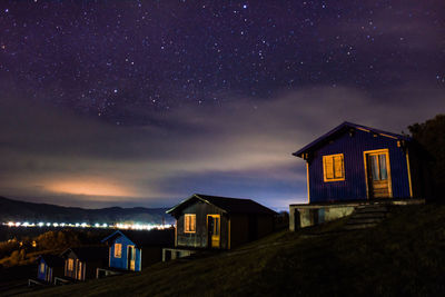 Illuminated houses against sky at night