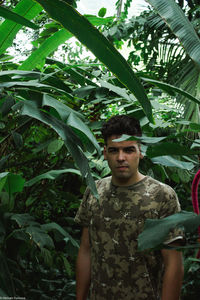 Portrait of young man standing against plants
