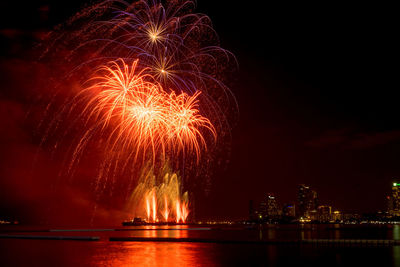 Illuminated firework display over river at night