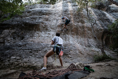 Rear view of men climbing rock