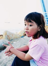 Portrait of happy girl holding pink while sitting outdoors