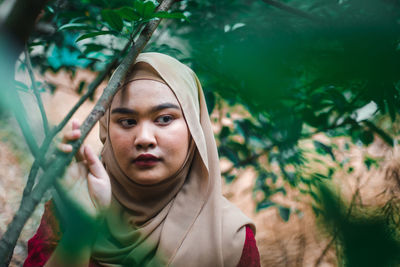 Young woman looking away by trees