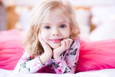 Portrait of cute girl sitting on bed at home