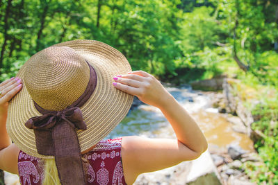 Rear view of woman holding hat on tree