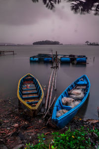 Abandoned boats moored at shore against sky