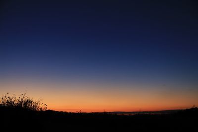 Scenic view of silhouette field against clear sky at sunset