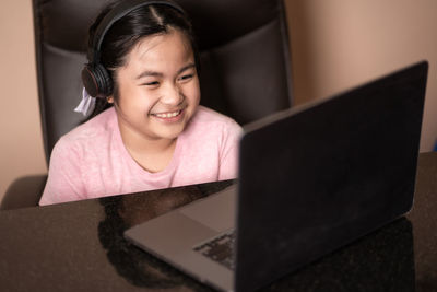 Portrait of smiling girl using mobile phone at home