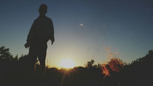 Silhouette of woman standing against sky at sunset