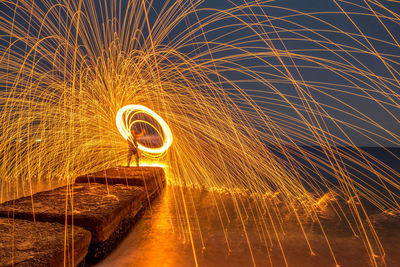 Man spinning wire wool at night