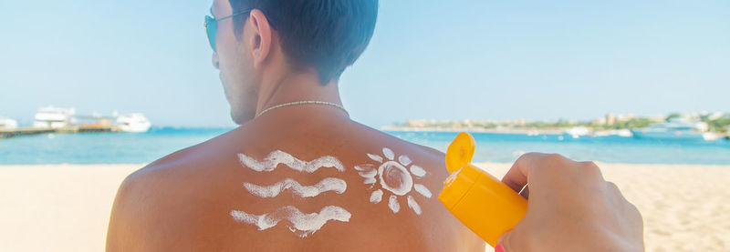 Midsection of man holding umbrella at beach