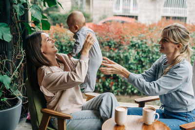 Two female friends are having a meeting in a cafe, one mother and friend are bonding with the baby.