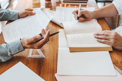 High angle view of people reading book on table