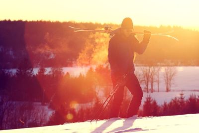 Full length of man standing on snowy field against sky during sunset